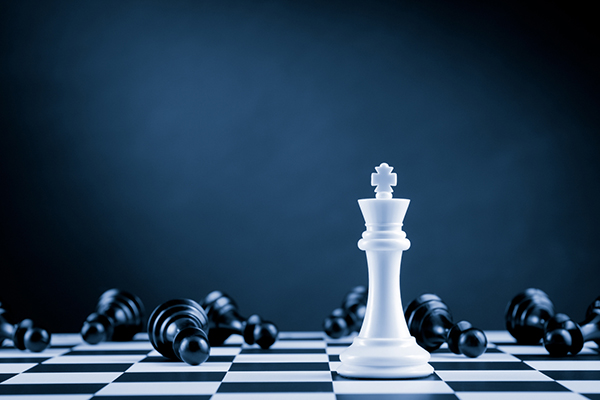 White chess king piece lying among black pawns on chessboard