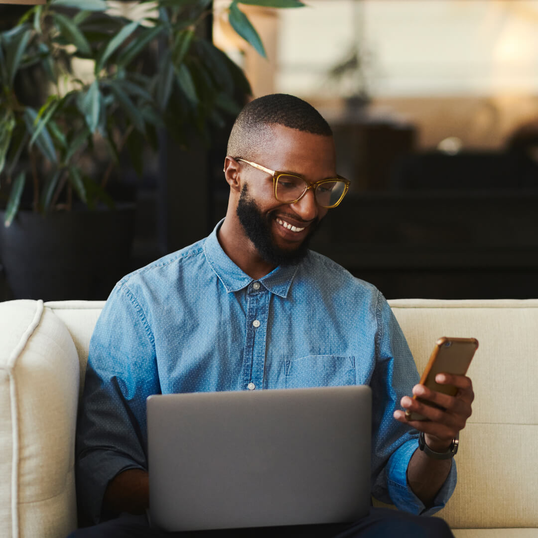 Man on sofa looking at devices