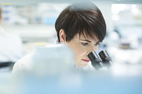 Female scientist looking into microscope in a lab