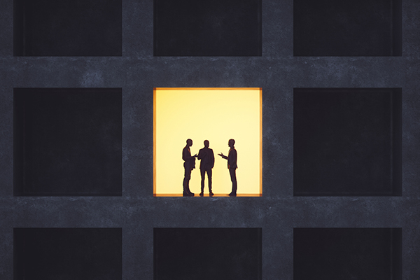 Three businessmen talking, backlit by a single light