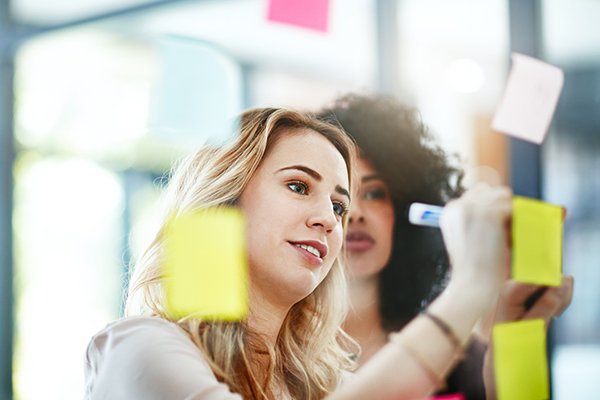 Two women writing on Post-It notes in the office