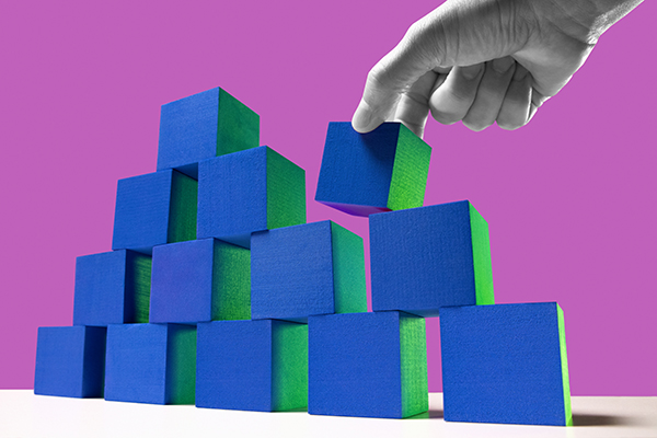 A hand adding cubes to a pyramid