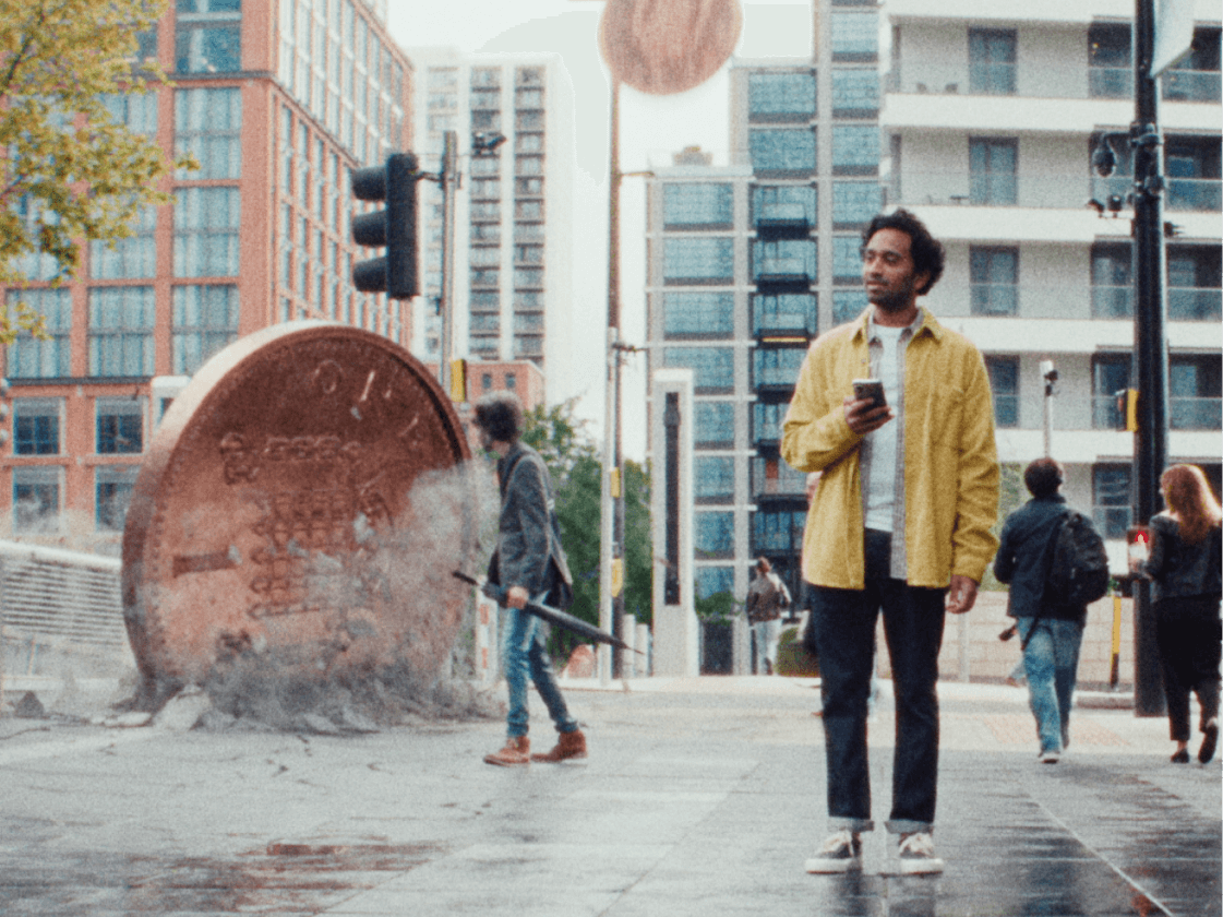 Man on phone with giant penny behind him