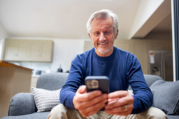Man sitting on the sofa looking at trust bargains on his iPhone