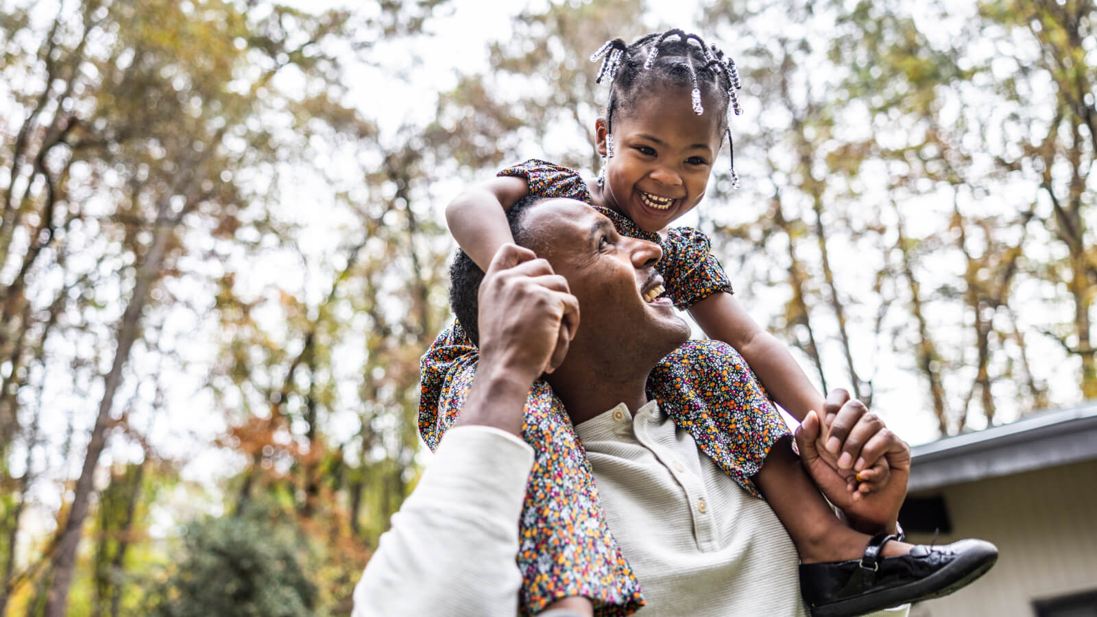 Smiling man with smiling child on his shoulders outside