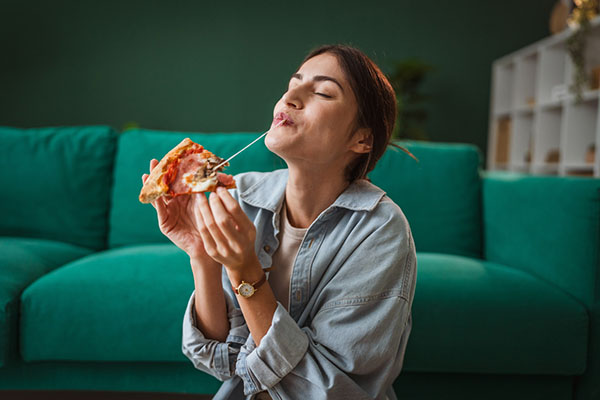 Woman eating slice of pizza at home