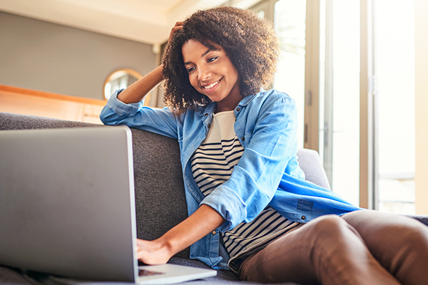 Woman sitting on the sofa considering ETFs on laptop
