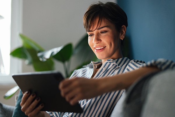 Woman smiling and reading a tablet computer