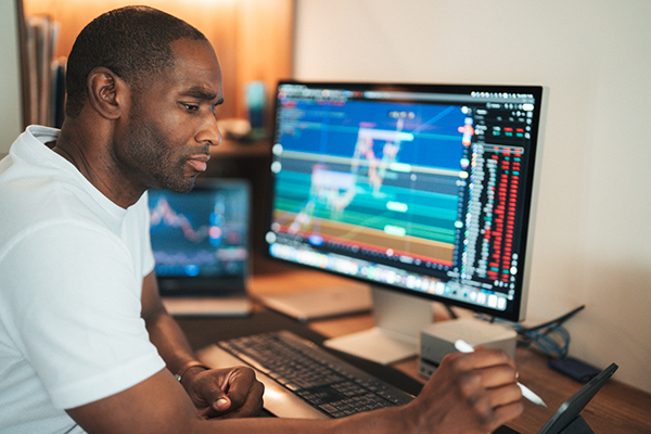 Man trading shares in front of screens