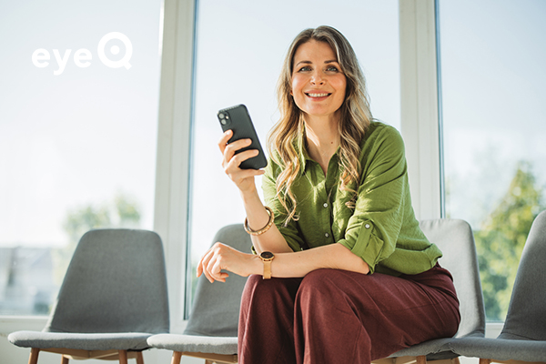 eyeQ woman sitting on a table looking at phone