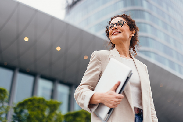 Businesswoman holding laptop and smiling