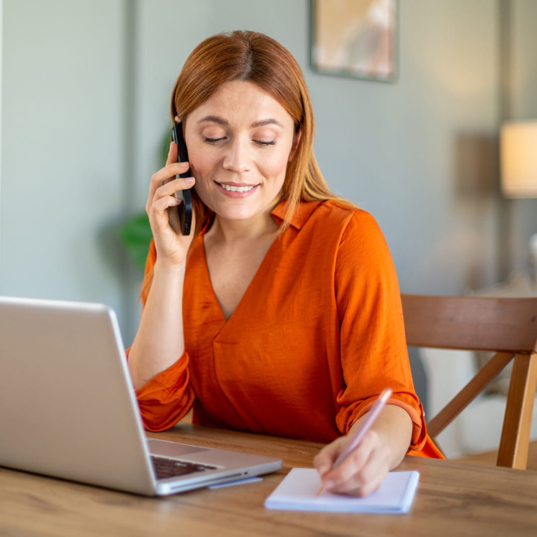 young woman laptop learning writing on phone orange