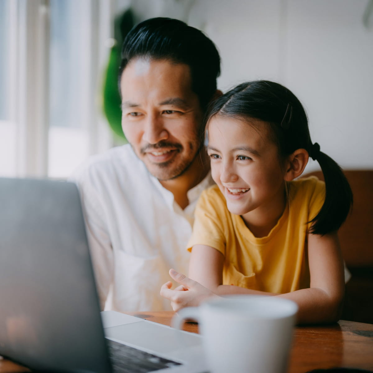 Man with daughter smiling at laptop indoors