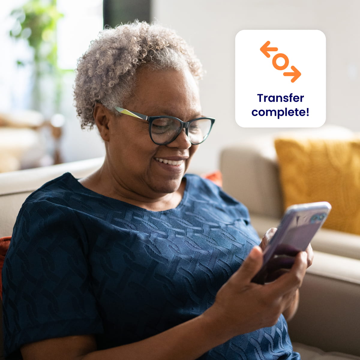 Mature woman with glasses smiling at mobile with transfer complete icon