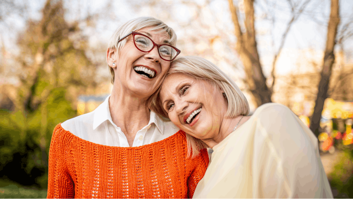 Two older women laughing and smiling outdoors