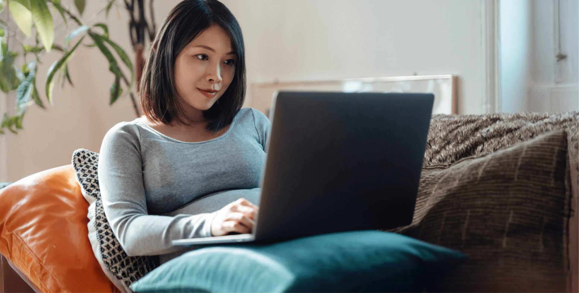 Woman sitting on sofa looking at laptop device