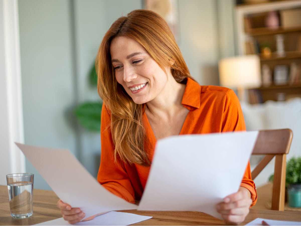 Young woman at table reading documents happy