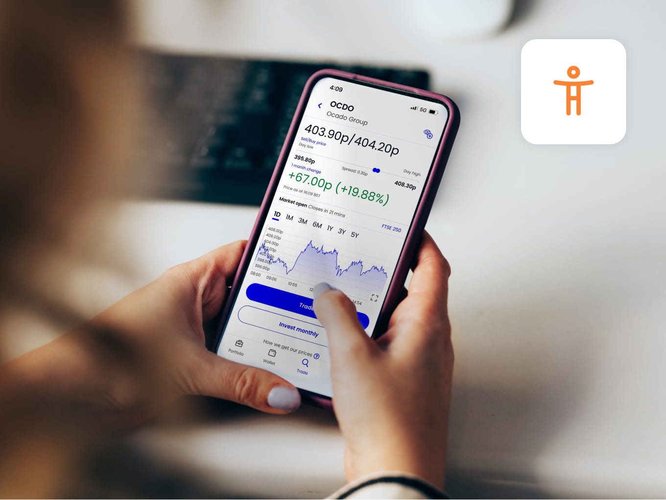 A woman holds a smartphone displaying the ii investment platform with stock prices and graphs. 