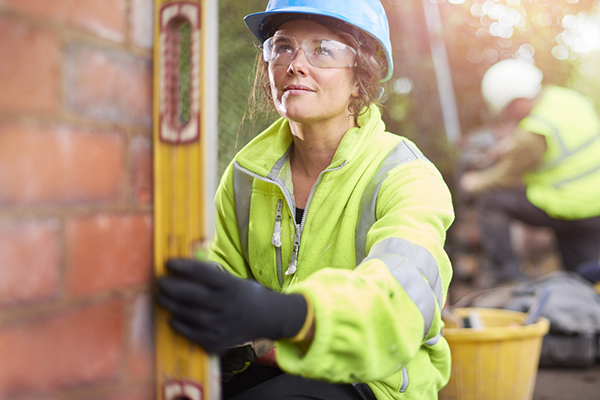 Female bricklayer checking levels