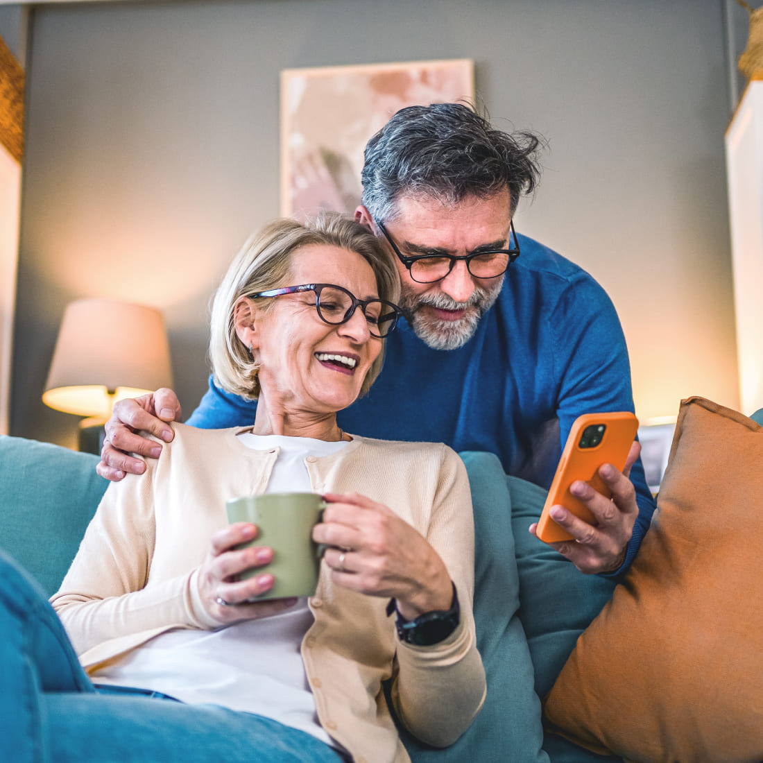 couple on couch smiling at mobile