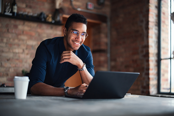 Man with laptop smiling and considering a trade