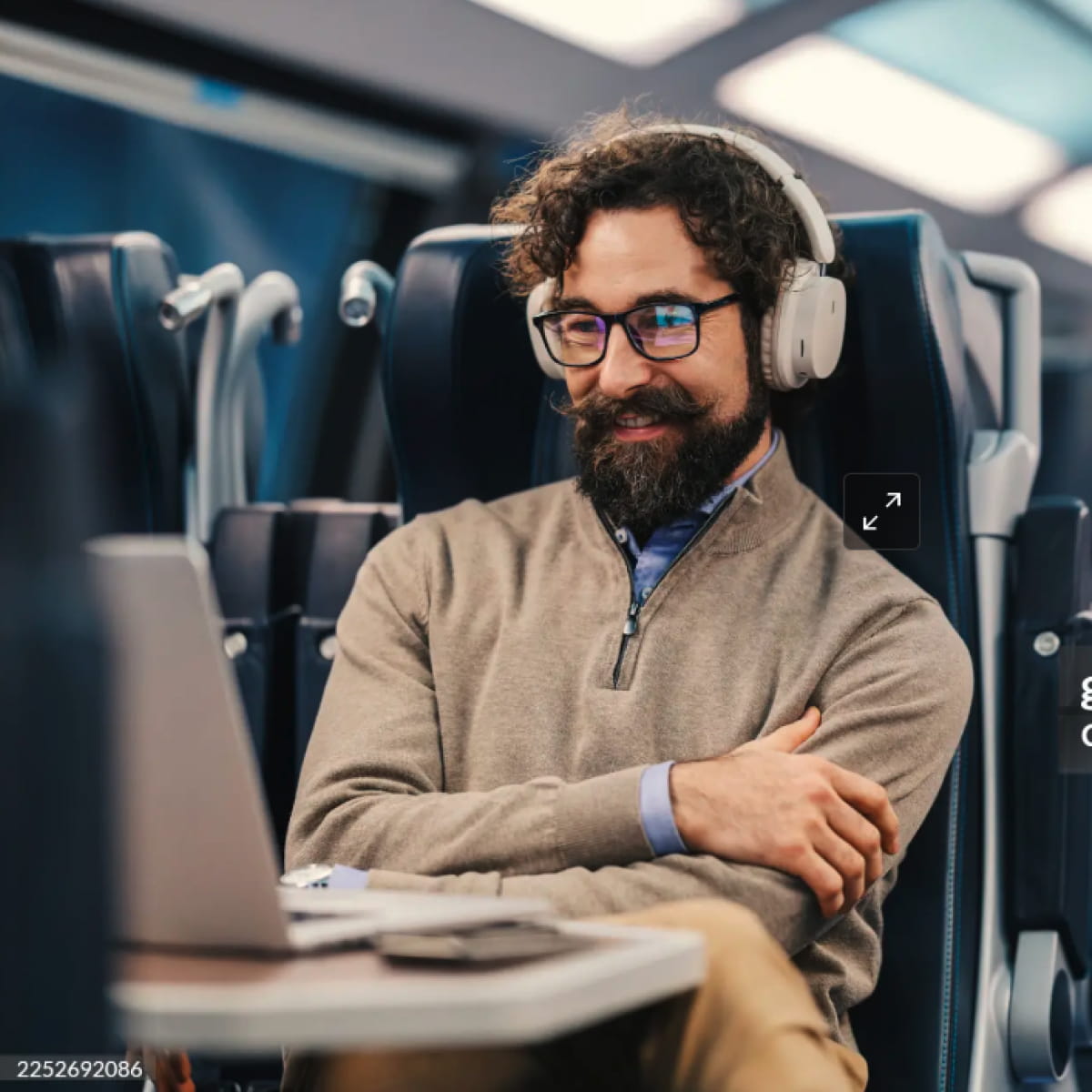 man on train reviewing investments on laptop