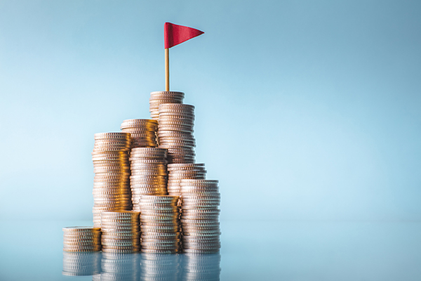 Piles of coins with red flag on summit