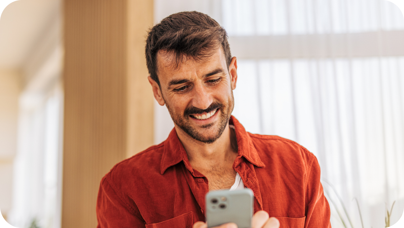 Man smiling at his phone at home
