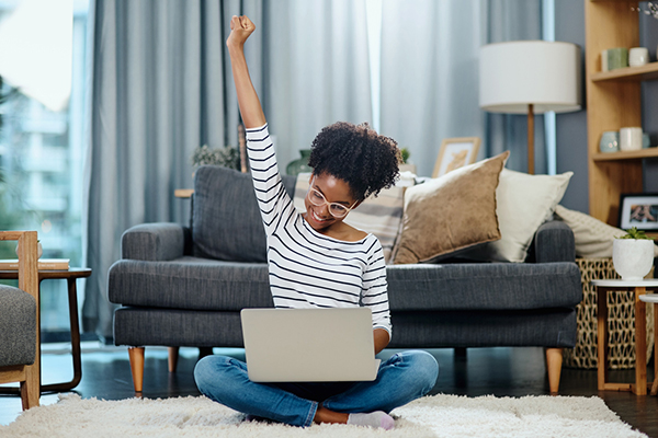 Woman doing a fist pump while looking at investments on laptop