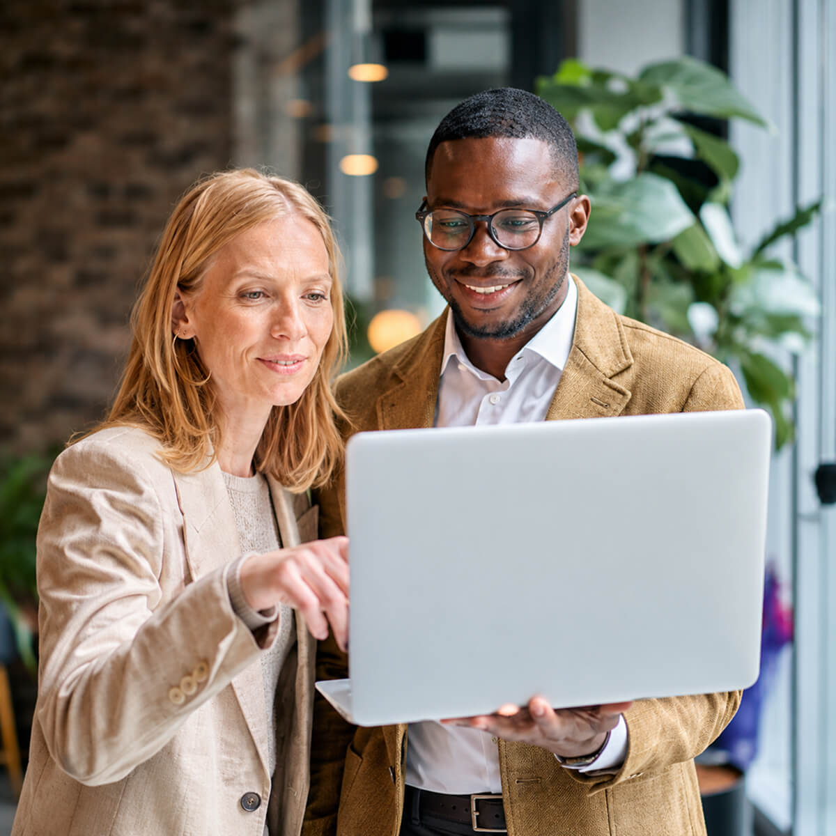 Smartly dressed man and woman with laptop in office