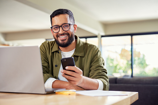 Investor smiling and looking at laptop and smartphone